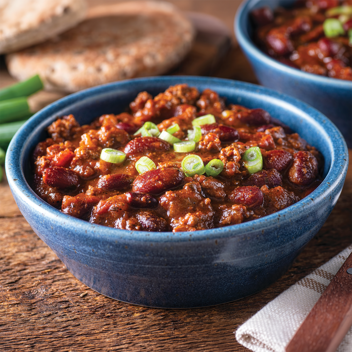 Sausage Chili in a blue bowl on a wooden table
