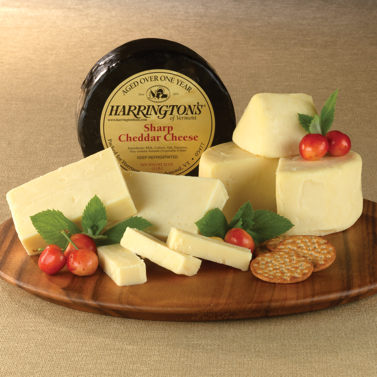 Aged Vermont Cheddar Cheese on a wooden tray with cherries and crackers.