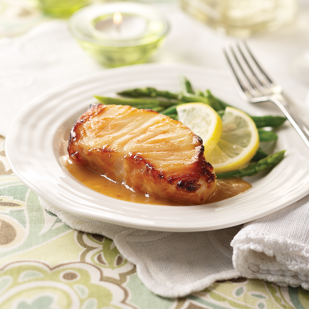 Miso Sea Bass fillet on a plate with green beans and lemon